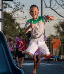 A boy in green shirt jumping on The Burger Shack playground.